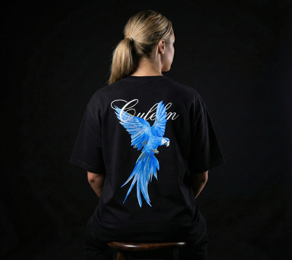Person wearing a black t-shirt with a blue macaw design on the back against a dark background