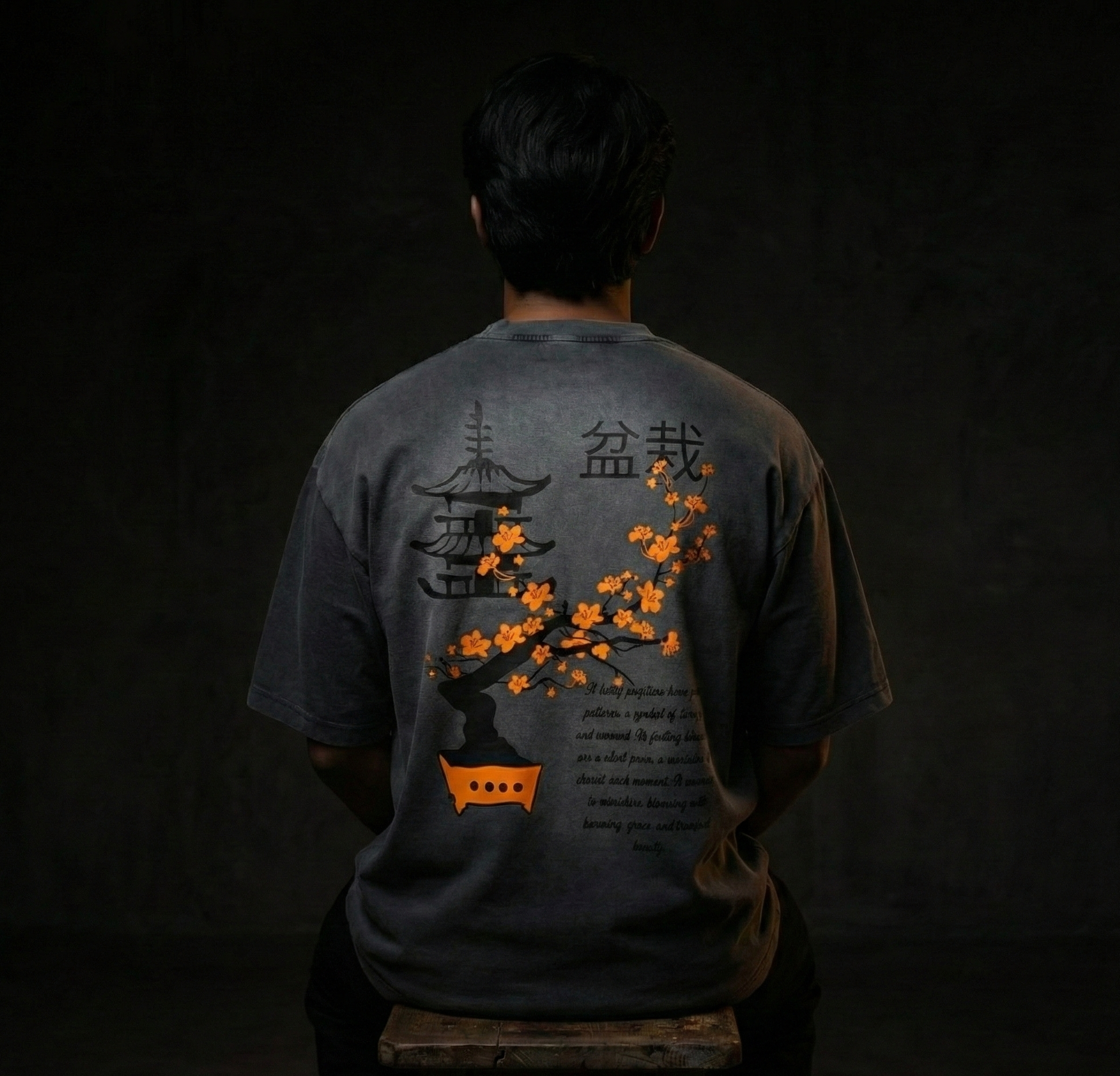 Person wearing a dark t-shirt with a Japanese-themed design on a dark background